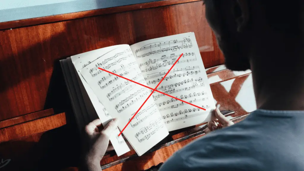 man looking at sheet music on top of a piano